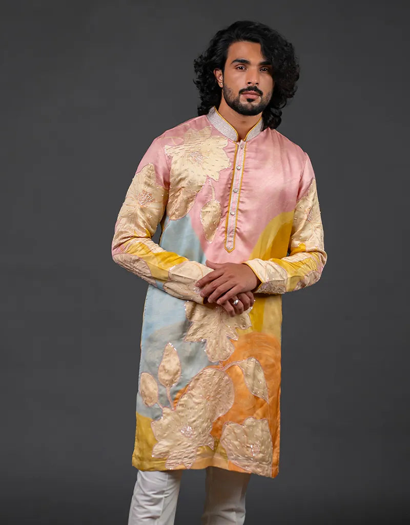 Man wearing a colorful kurta with a gradient design on a dark background