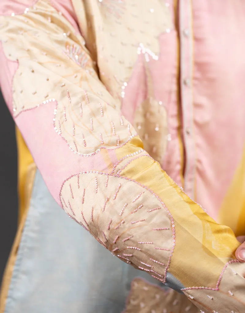 Close-up of a Abstract Embroidered Kurta Set with intricate embroidery on a pink and yellow fabric.