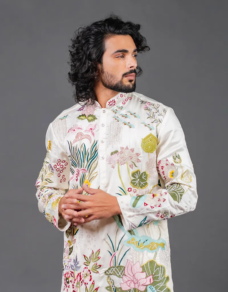 Man wearing a floral embroidered shirt against a gray background