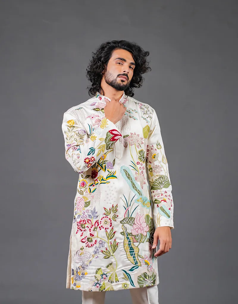 Man wearing a floral embroidered kurta against a gray background