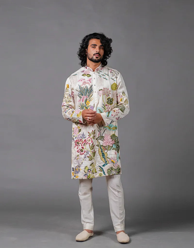 Man wearing a floral kurta with white pants against a gray background