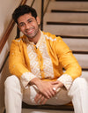 Man wearing a yellow traditional Marigold Heritage Embroidered Kurta outfit sitting on stairs