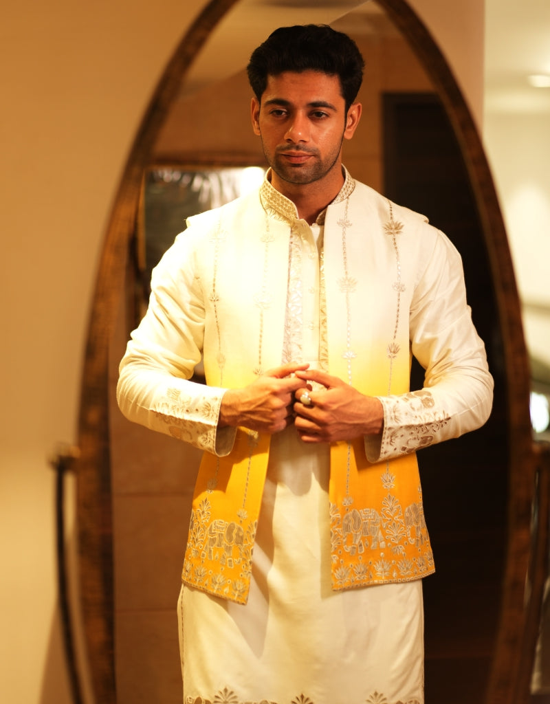 Man wearing a traditional Golden Horizon Ombre Bandi Set outfit with a yellow and white design in front of a mirror.