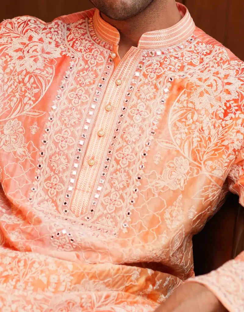 Close-up of a person wearing an orange embroidered traditional outfit.