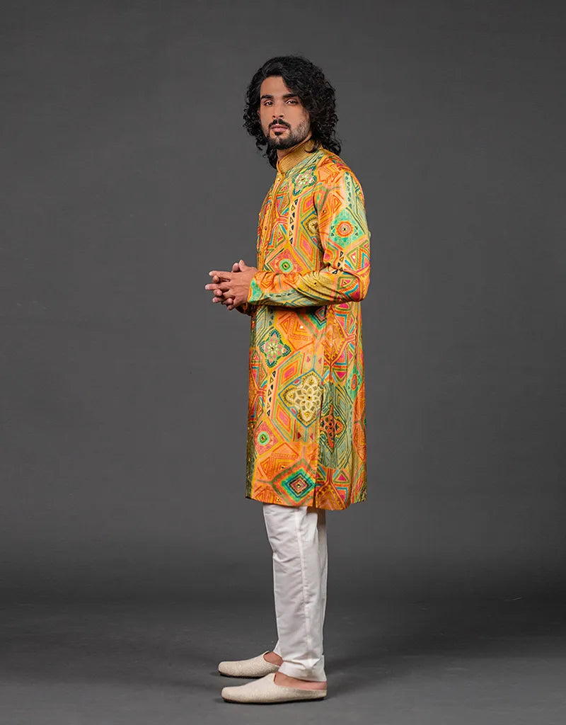 Man wearing a colorful Heritage Silk Kalamkari Kurta with white pants on a gray background
