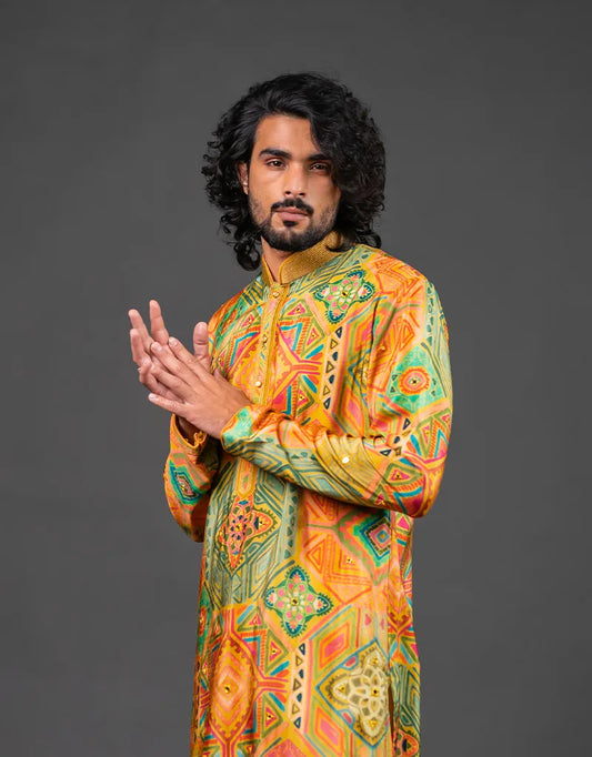 Man wearing a colorful traditional Heritage Silk Kalamkari Kurta outfit against a gray background