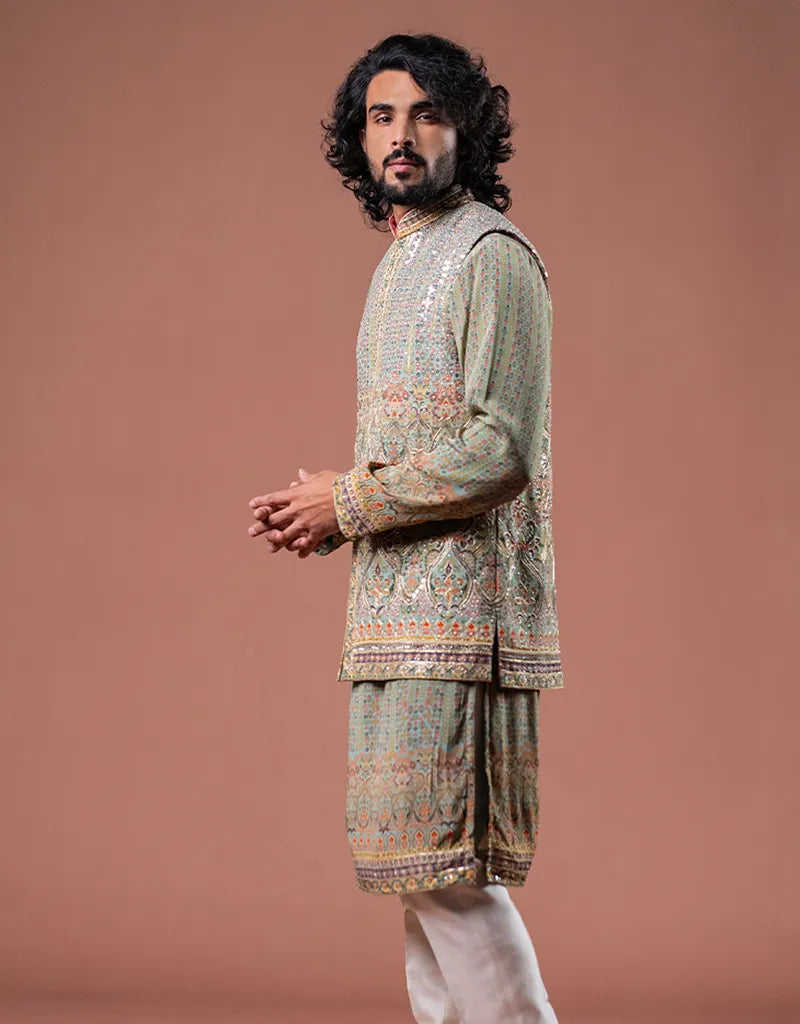 Man wearing a patterned Kalamkari Gotta Bandi Kurta Set with dhoti pants against a brown background