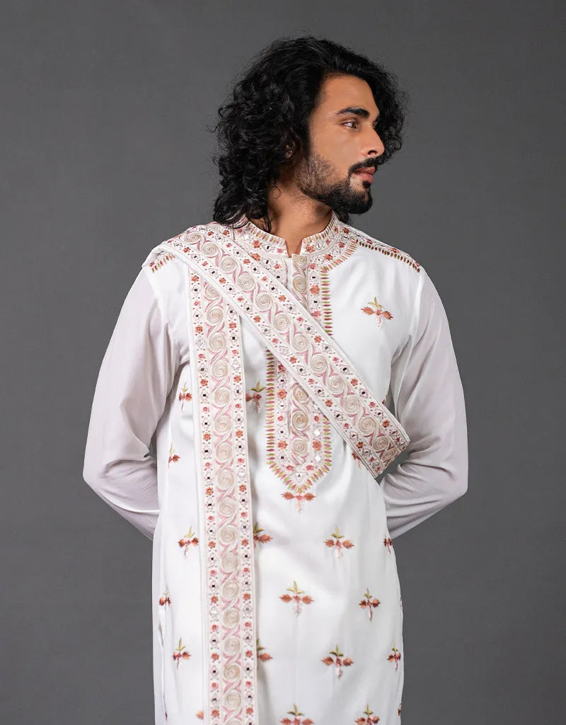 Man wearing a white Kashmiri Mirror Kurta Set with intricate embroidery against a gray background