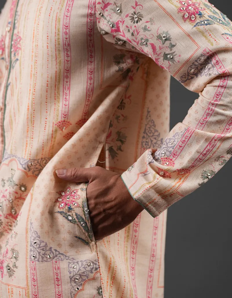 Close-up of a hand holding a piece of embroidered Khadi Mirror Work Kurta fabric with floral patterns.