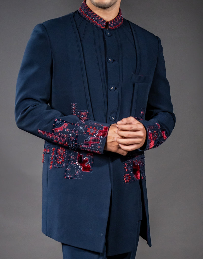 A man wearing a three-piece Jodhpuri suit in blue with applique patchwork and hand embroidery from The HUB.