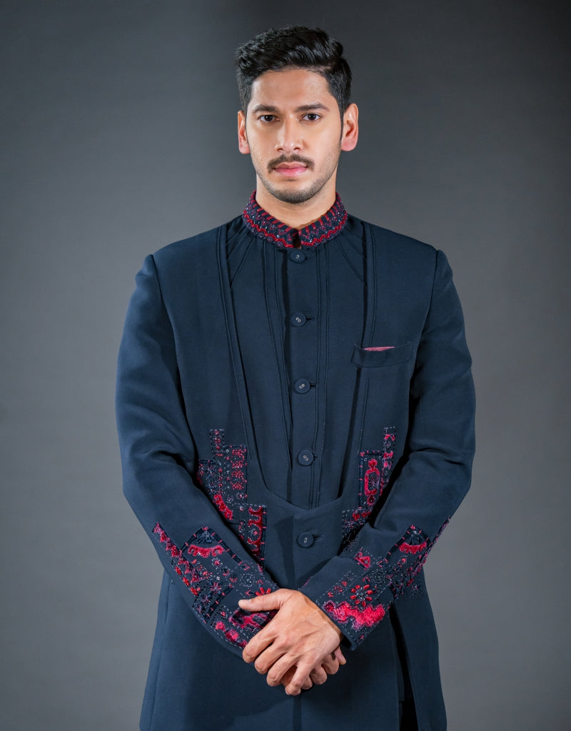 A man wearing a three-piece Jodhpuri suit in blue with applique patchwork and hand embroidery from The HUB.