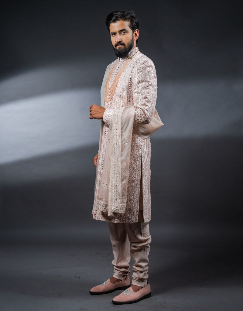 A man wearing the Four-piece Exquisite Mirrorwork Sherwani in Dusty Pink from The HUB.