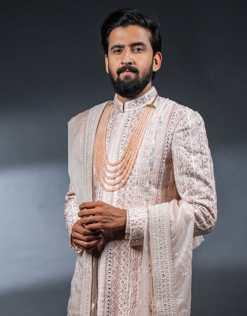 A man wearing the Four-piece Exquisite Mirrorwork Sherwani in Dusty Pink from The HUB.