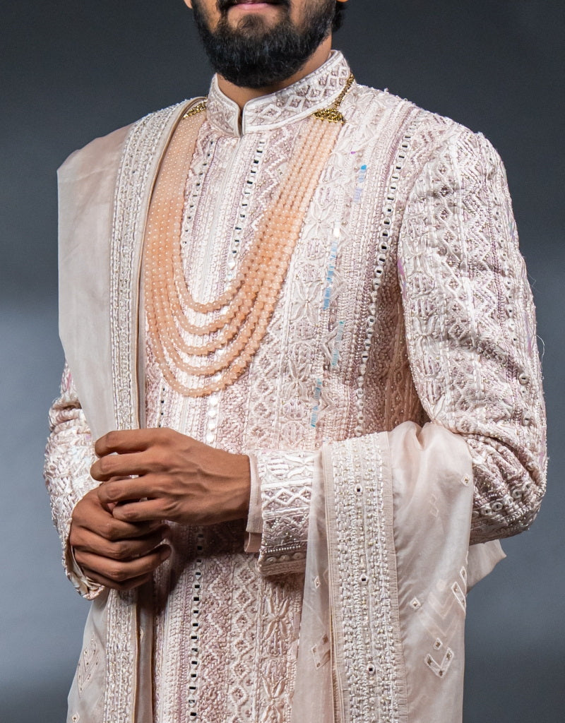 A man wearing the Four-piece Exquisite Mirrorwork Sherwani in Dusty Pink from The HUB.