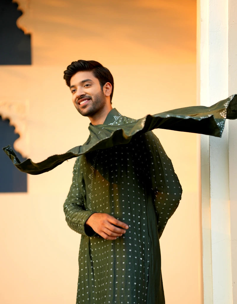 Man wearing a green traditional Verdant Elegant Kurta Set outfit with a decorative design against a warm-toned background