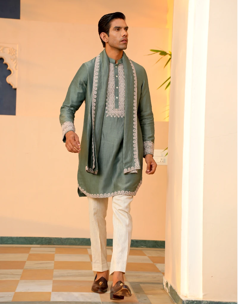 Man wearing a traditional green kurta with white pants in an indoor setting.
