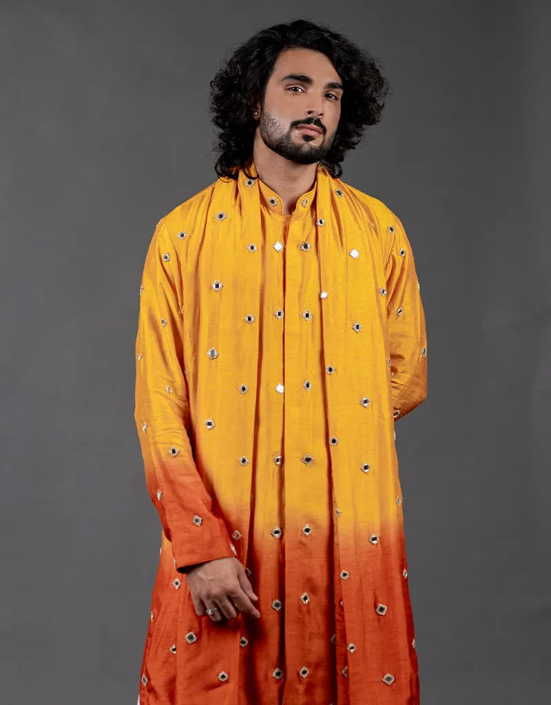 Man wearing a yellow to orange gradient kurta with decorative patterns on a gray background