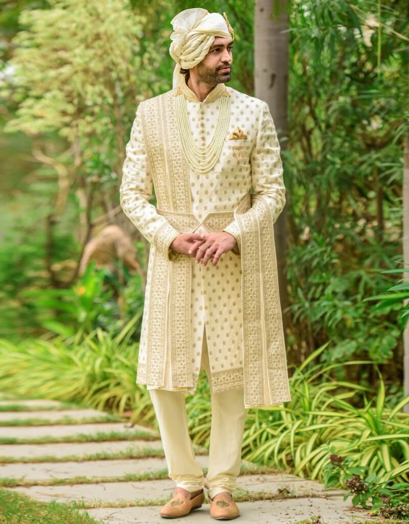 A man wearing a four-piece sherwani in raw silk with gold inlay boota work—cream from The HUB.