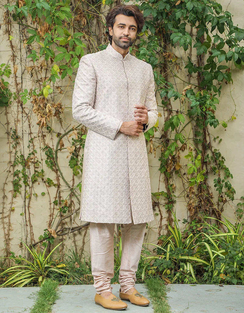 A man wearing a three-piece sherwani in satin silk with resham & pearls in onion pink from The HUB.