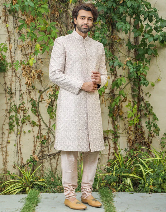 A man wearing a three-piece sherwani in satin silk with resham & pearls in onion pink from The HUB.