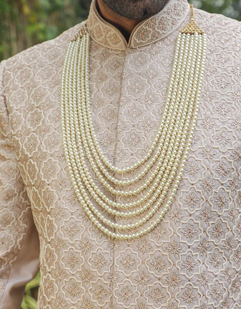 A man wearing a three-piece sherwani in satin silk with resham & pearls in onion pink from The HUB.