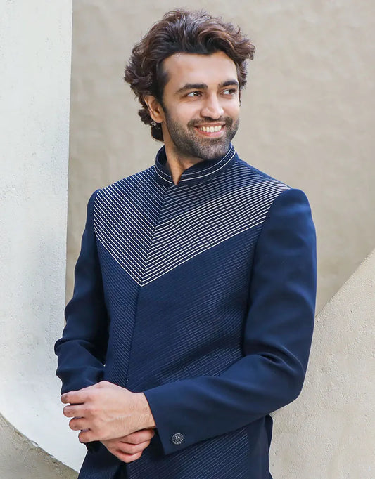 A man wearing a two-piece Daghai Jodhpuri suit with self-threaded work in black/navy blue from The HUB.