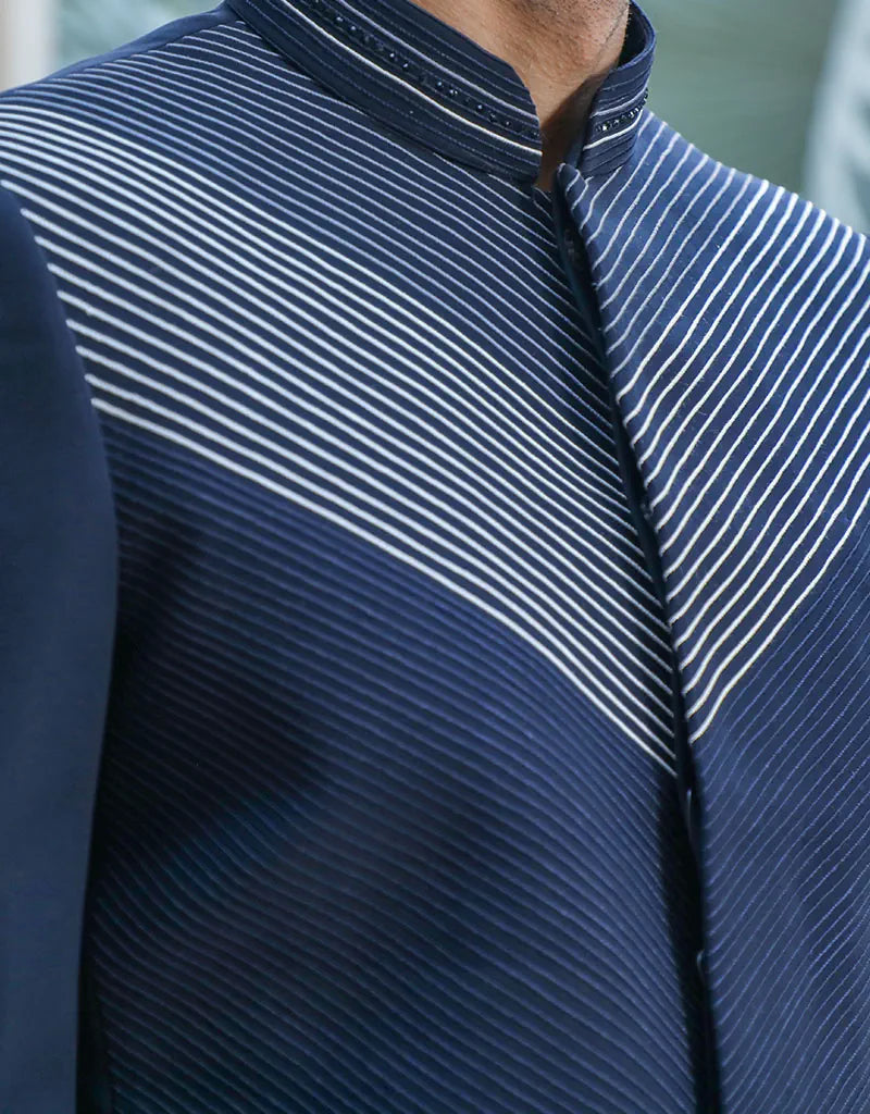 A man wearing a two-piece Daghai Jodhpuri suit with self-threaded work in black/navy blue from The HUB.