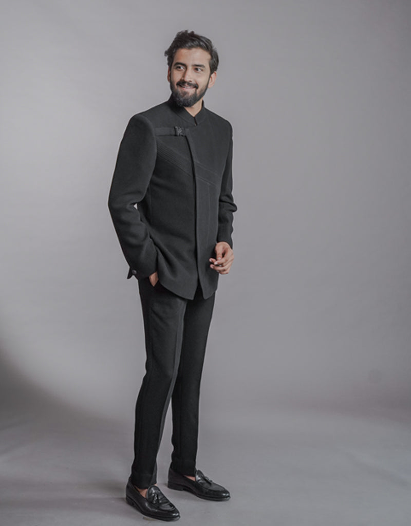 A man wearing two-piece Jodhpuri suit of netted, stretched fabric in black from The HUB.