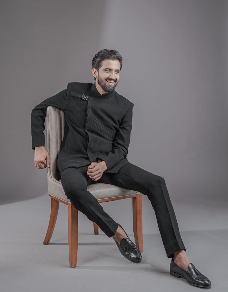 A man wearing two-piece Jodhpuri suit of netted, stretched fabric in black from The HUB.