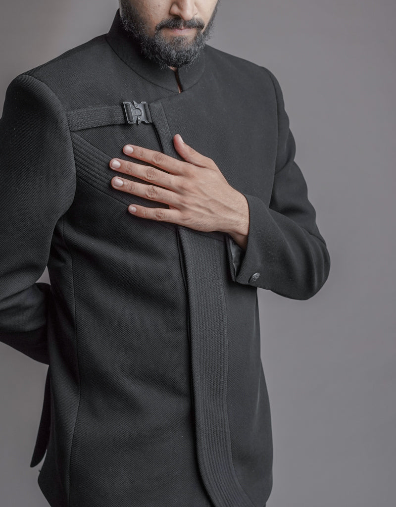 A man wearing two-piece Jodhpuri suit of netted, stretched fabric in black from The HUB.