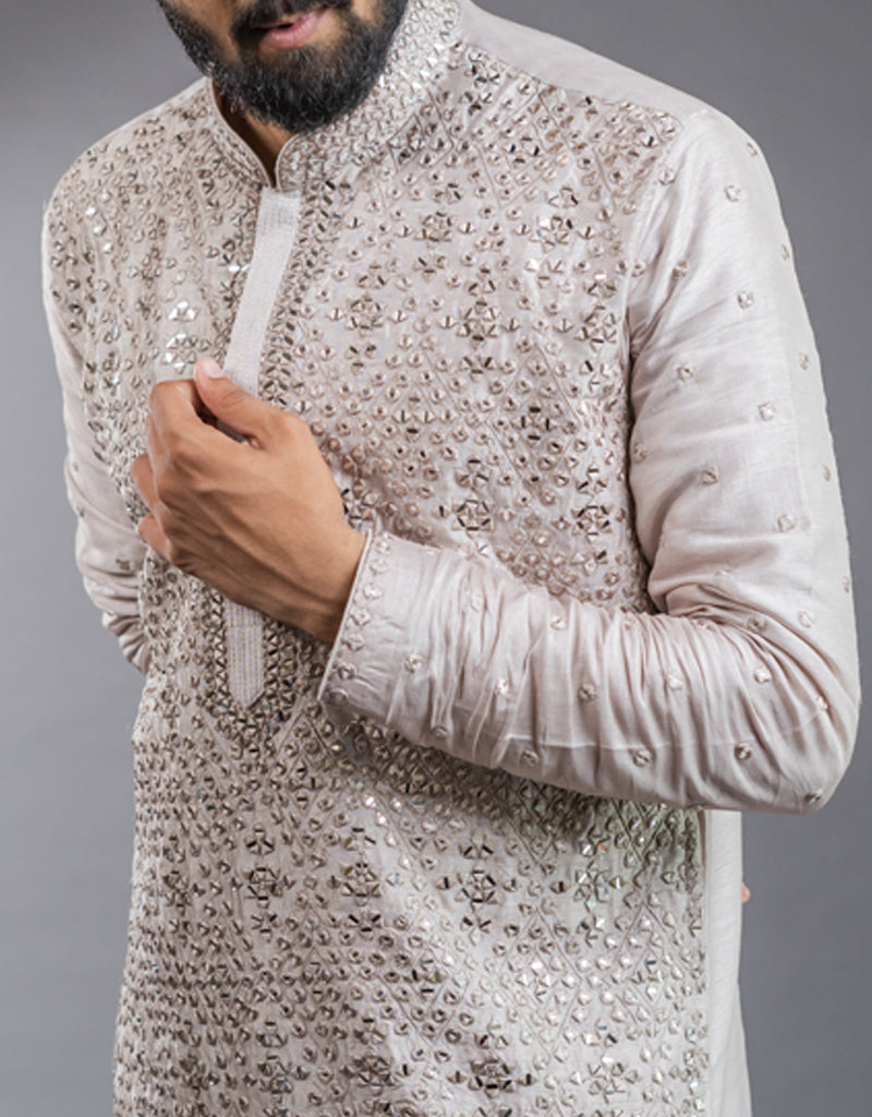 Man wearing a beige embroidered One-Piece Satin Silk Kurta in Light Onion against a gray background
