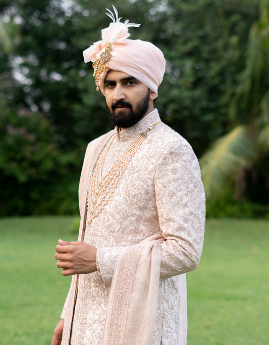A man wearing a four-piece sherwani with a pure Jamewaram Anarkali kurta in dusty rose from The HUB.
