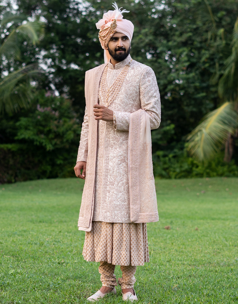 A man wearing a four-piece sherwani with a pure Jamewaram Anarkali kurta in dusty rose from The HUB.