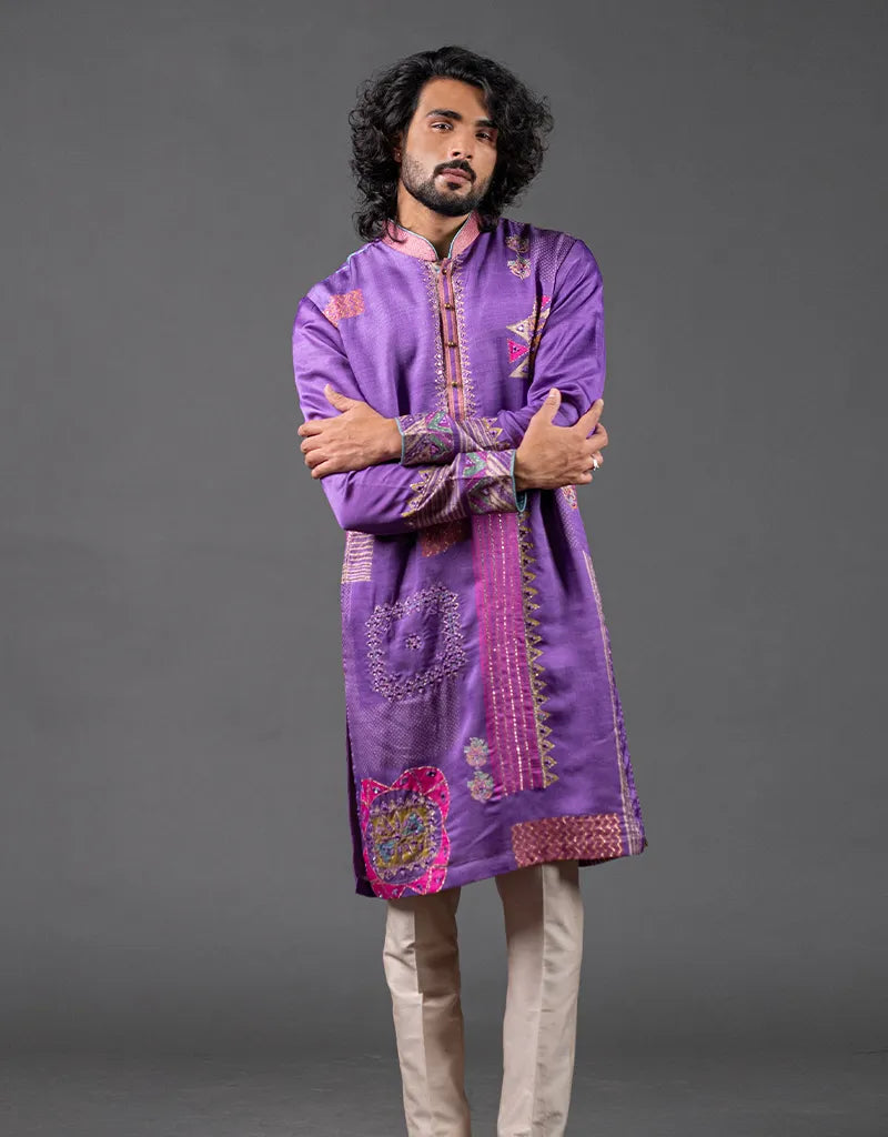 Man wearing a purple embroidered kurta against a gray background