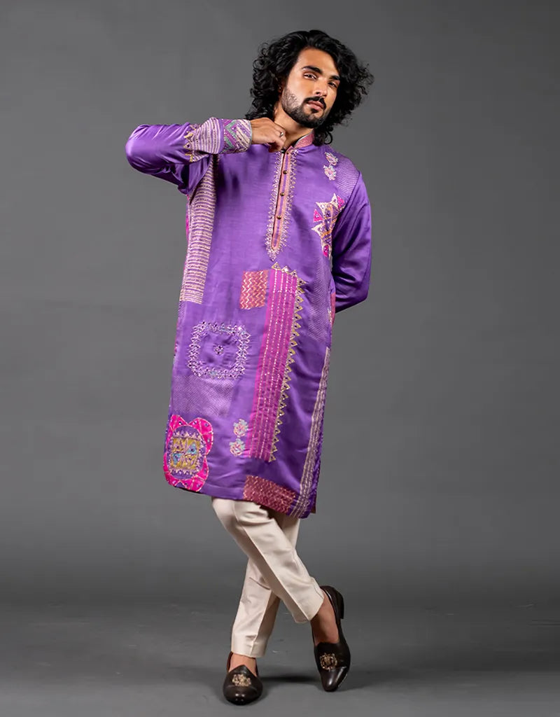 Man wearing a purple embroidered kurta with white pants on a gray background